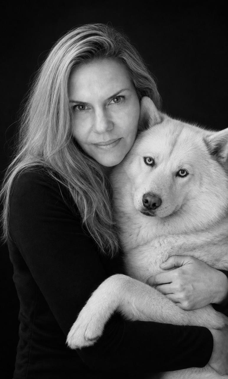Carla Schmitt, co-founder, in a black-and-white portrait holding a white dog.